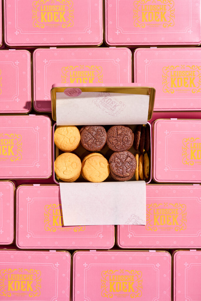 Geopend koekblik met koeken, tussen gesloten roze blikken